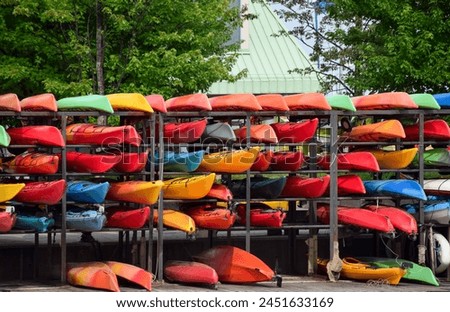 Multiple colourful kayaks on storage shelves at a rental station in the summer Royalty-Free Stock Photo #2451633169