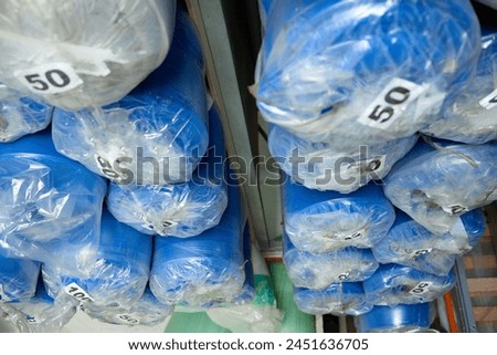 Rolls of foam sheets are neatly stacked on shelves in storage. Stocks of soft blue foam rubber in the warehouse of a furniture factory