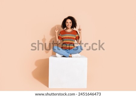 Full body photo of pretty girl wear ornament t-shirt sit on platform indicating at promo empty space isolated on pastel color background