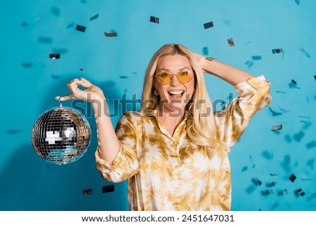 Photo portrait of stunning mature lady hold discoball celebration dressed stylish formalwear clothes isolated on cyan color background