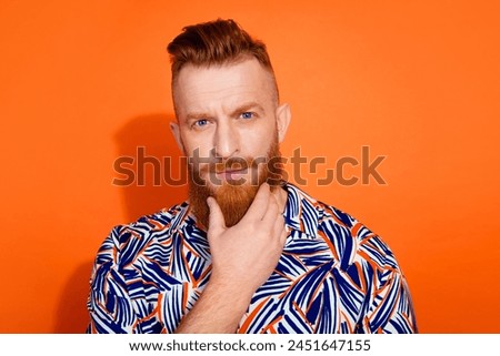 Photo of serious confident guy dressed print shirt arm chin empty space isolated orange color background Royalty-Free Stock Photo #2451647155