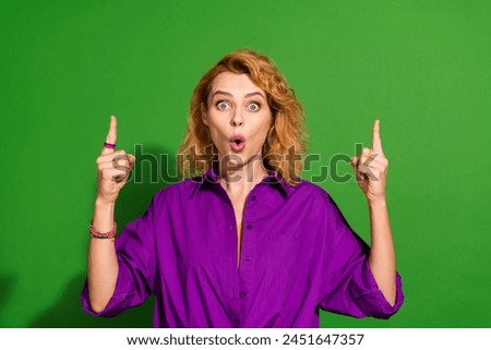 Photo portrait of pretty young girl point up shocked empty space banner wear trendy purple outfit isolated on green color background