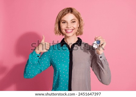 Photo portrait of pretty young girl hold keys new house thumb up wear trendy striped cyan outfit isolated on pink color background