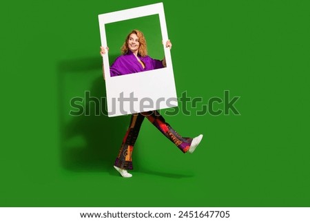 Photo portrait of lovely young lady walk hold instant photo frame dressed stylish violet clothes isolated on green color background