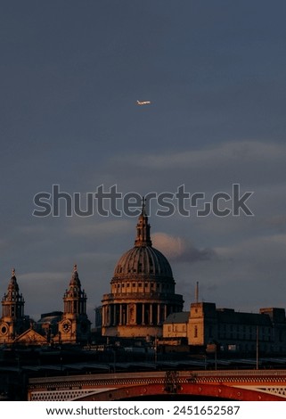 A plane flying over St. Paul’s cathedral dome in London, taken at sunset