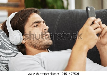 Man, headphones and phone for music on couch, relax and listen to song and scroll on social media. Male person, home and rest app for playlist or conversation, text and podcast audio for streaming