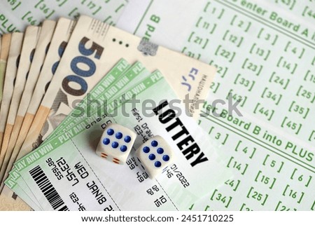Green lottery tickets and ukrainian money bills on blank with numbers for playing lottery close up