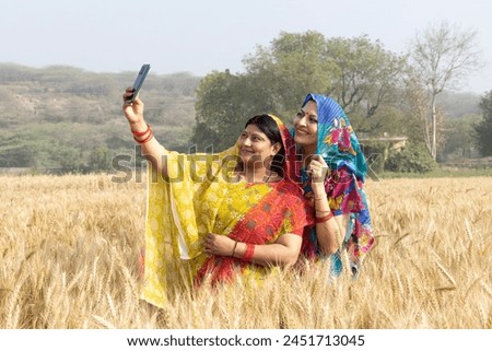 Indian rural women taking selfie picture while standing on wheat crop agriculture field