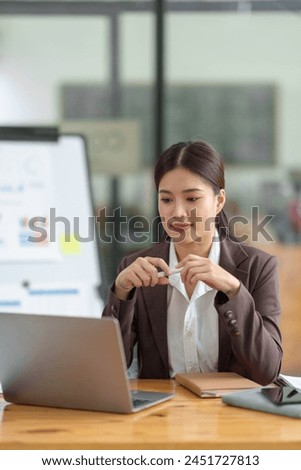 Asian businesswoman sitting and thinking analyze financial reports Business growth using laptop computer and documents, graphs, charts, investment calculators. Office business plan