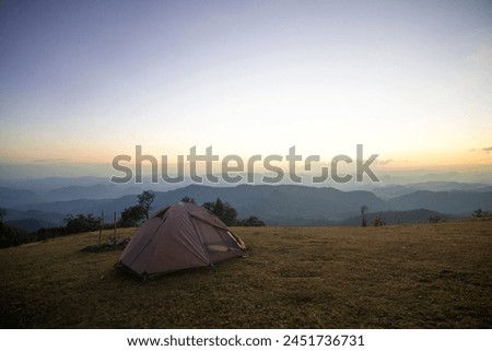 Camping tent at night. tent by the warm glow of sunrise as a golden cloudscape reveals the dramatic mountain pinnacles of this panoramic landscape.