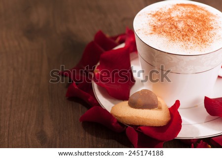 I love you. Closeup image of lovely heart shape cookie with chocolate and cup of coffee placed with copy space on wooden table and decorated with rose petals