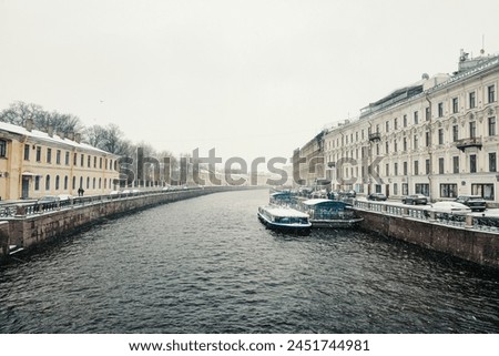 A pleasure boat is moored on the river in a spring snowstorm. Saint-Petersburg. Russia. Early spring navigation on the river in very bad weather, the beginning of the tourist season in St. Petersburg.