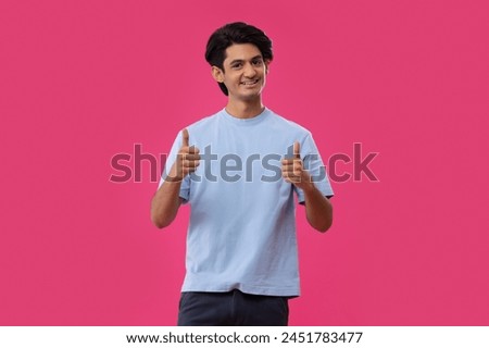 Portrait of smiling teenage boy gesturing while standing against pink background