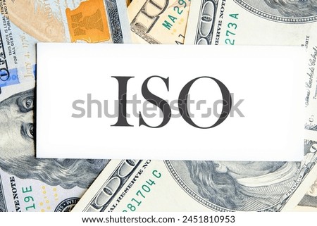 ISO. International Organization for Standardization. A Word ISO on a white business card lying on dollars