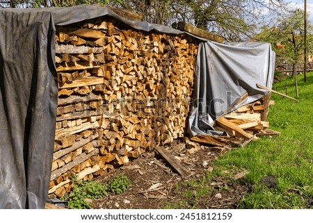 Close-up of stapled firewood with gray cover at Swiss village of Kehrsiten on a sunny spring day. Photo taken April 11th, 2024, Kehrsiten, Switzerland.