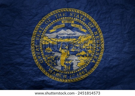 colorful big national flag of nebraska state on a grunge old paper texture background