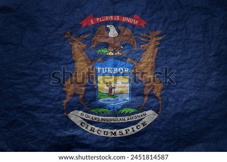 colorful big national flag of michigan state on a grunge old paper texture background