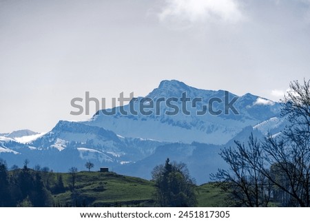 Scenic rural landscape with snow covered mountains in the background seen from Swiss Bürgenstock mountain on a sunny spring day. Photo taken April 11th, 2024, Bürgenstock, Switzerland.
