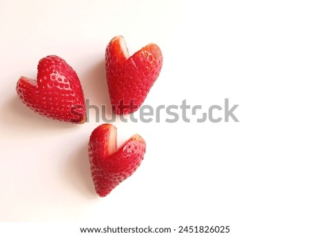 Top view of three heart shaped juicy strawberries on the white background with a copy space.