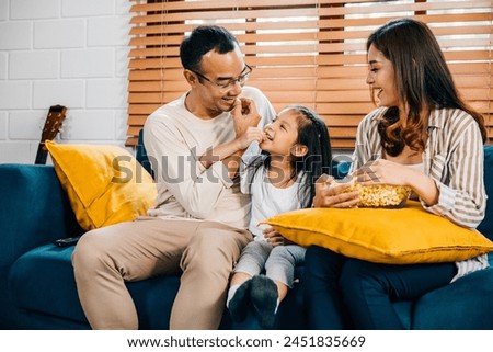 A modern family sits on grooved sofa enjoying togetherness while watching TV with popcorn. father mother daughter and sibling share laughter smiles and moments of joy during their quality family time.