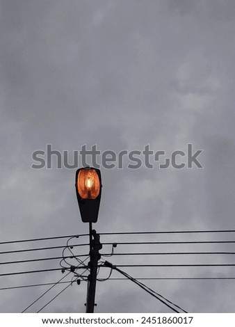 Picture of a dim light street lamp with a dark and moody weather from below.