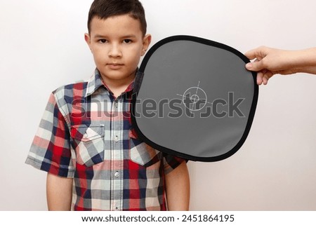 In the photo studio, a gray card is placed next to the boy to register the correct camera colors. Working in the studio is a process of photography.