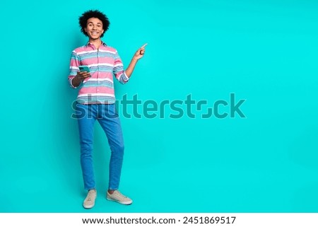 Full length photo of happy positive man wear stylish striped clothes introduce empty space isolated on cyan color background