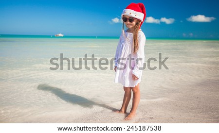 Little adorable girl in red Santa hat at tropical beach