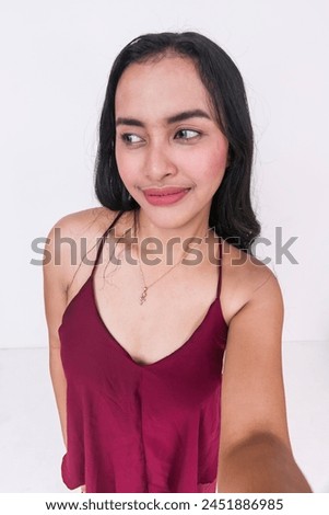 A vibrant image of a young Asian lady wearing a chic maroon dress and taking a selfie. The overhead shot isolates her against a white background.
