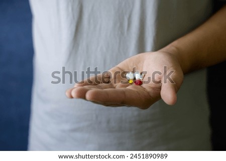 A man holds medicine in his hand. This picture represents Medicine medicine, antibiotics, hand holding pill capsules, taking cold medicine, tonic, flu, painkillers, vitamins for treatment, pharmacy an