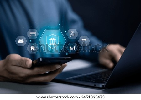 Businessman using smartphone and laptop with insurance icon on virtual screen. Deposit protection, bank insurance, financial security and bank run prevention concept. Royalty-Free Stock Photo #2451893473