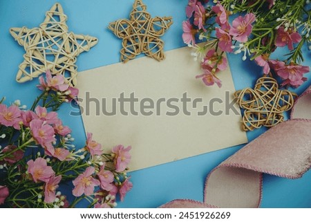 Invitation or greeting card mockup and flower decoration top view on blue background