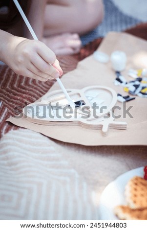 A girl creates a bee from a ceramic mosaic in an open space. 