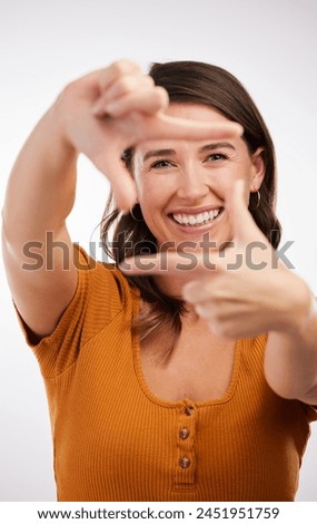 Finger frame, portrait and cheerful woman in studio for photography, perspective or focus with white background. Model, happiness and face of female person with hand gesture, symbol or capture