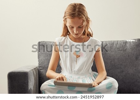 Typing, home and girl on sofa, tablet and digital app for games, social media and online cartoon. Apartment, child development or kid with tech, internet or connection to reading ebook and network