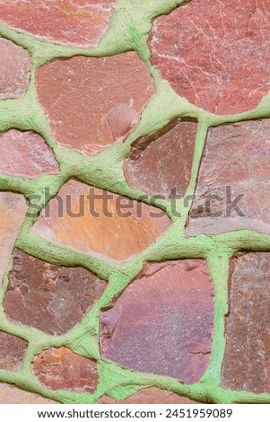 It is photo of colorful stones on green background. Its close up of multicolored stone wall of building. It is photo of the mosaic tile floor