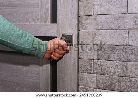 A man's hand opens the door with a chrome handle Royalty-Free Stock Photo #2451960239