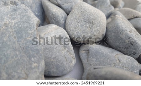 Closeup of gray pebbles placed on a white background with natural light. The photography is of high resolution with professional color grading and no added contrast. The focus is clean and sharp