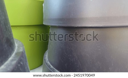 Close up of dark grey and lime green plastic pots stacked on top of each other, macro photography, product photo for a website, no shadows, neutral background, in the style of no artist