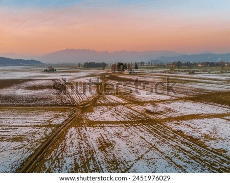 Domzale - menges field in the winter at the sundet with Kamnik-Savinja Alps in the background, Slovenia Royalty-Free Stock Photo #2451976029
