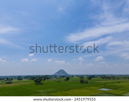 drone shot aerial view top angle bright sunny day beautiful scenery natural tourism destination India tamilnadu madurai ruralscape mountain background blue sky paddy rice fields empty space wallpaper 
