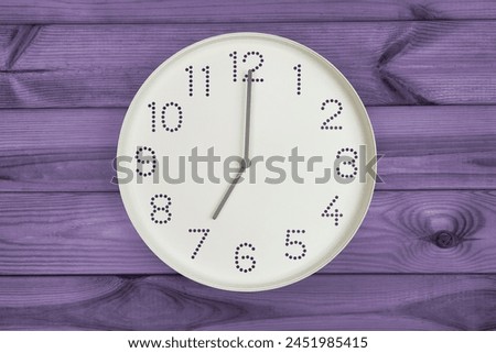 Round white wall clock at 7 o'clock on purple wood background. concept of daily regime, wake up time, Morning Vitality, Evening Relaxation Royalty-Free Stock Photo #2451985415