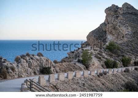A winding coastal road meanders along rugged terrain, leading the eye to the merging of sea and sky at dusk. High quality photo
