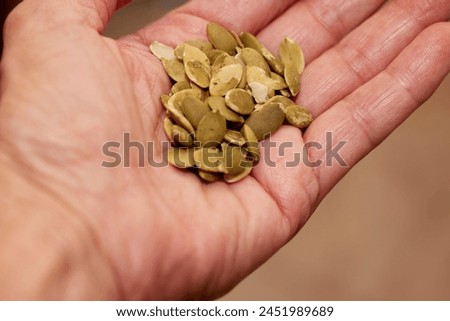 Close up of organic pumpkin seeds cupped in the palm of a hand