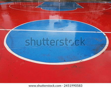 Rain-soaked blue red background colored basketball court