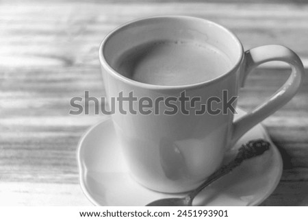 Black and white picture of coffee crema in a white cup with spoon on a wooden table in Luang Prabang Laos.