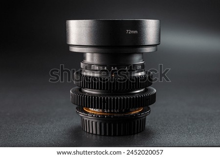 Vintage camera lenses stacked, 72mm marking on top, detail of aperture scale visible, essential for professional photography, set against a dark background.