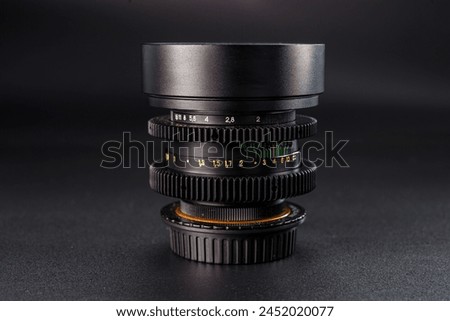 Macro view of stacked camera lenses with aperture and focus markings, precision engineering for photography, on a dark textured surface, highlighting details