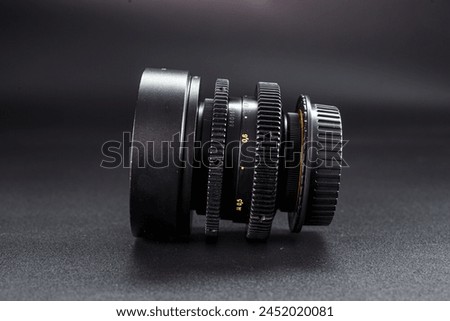 Side angle of antique camera lens showcasing focus dials, numbered settings, photography enthusiasts collectible, placed against gradient dark background