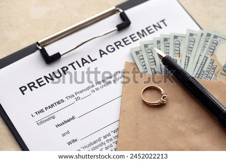 Prenuptial agreement and wedding ring on table. Premarital paperwork process in USA close up Royalty-Free Stock Photo #2452022213